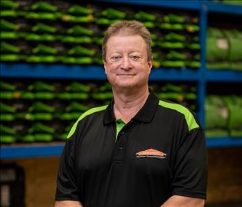 Ricky is a white male with sandy brown hair. Wearing a black and green servpro polo