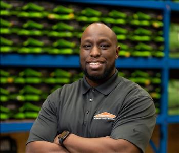 Gerald is a black male who is bald and is wearing a black servpro polo