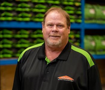 Mark is a white male with brown hair wearing a black and green servpro polo