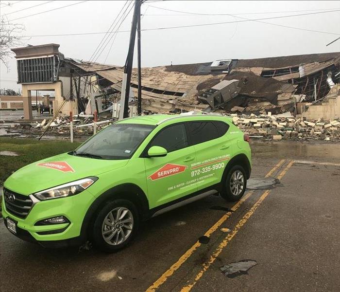 SERVPRO Green Toyota SUV in front of a collapsed tan commercial build