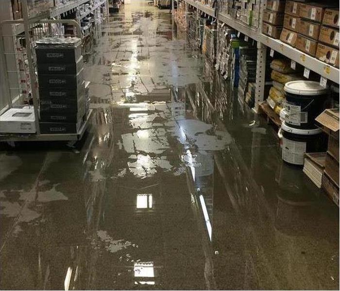 water on this commercial building floor with shelving on sides